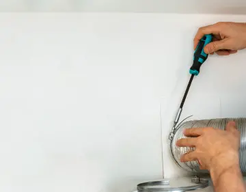 un technicien en bleu répare ou entretient une vmc