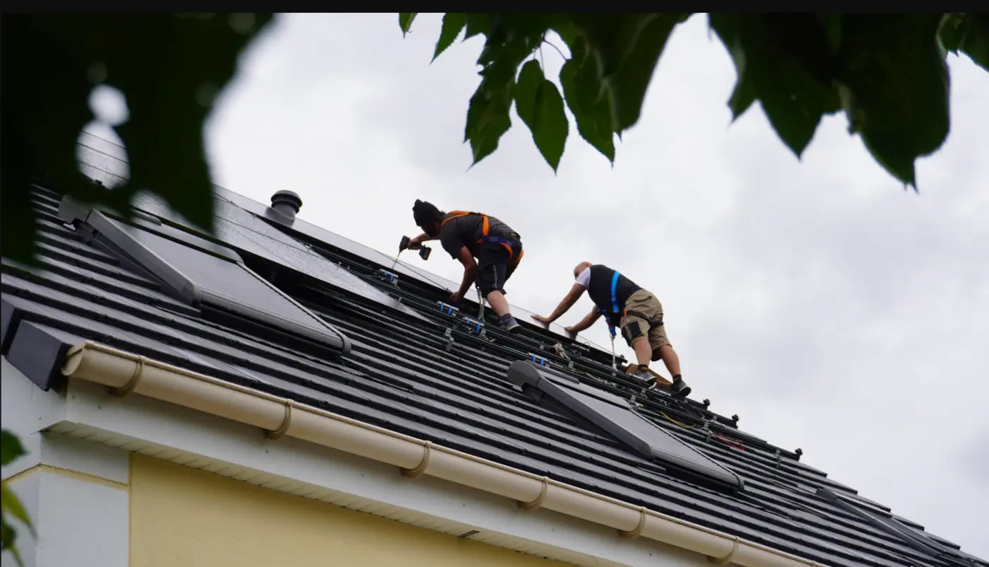 Deux installateurs en train d'installer des panneaux solaires