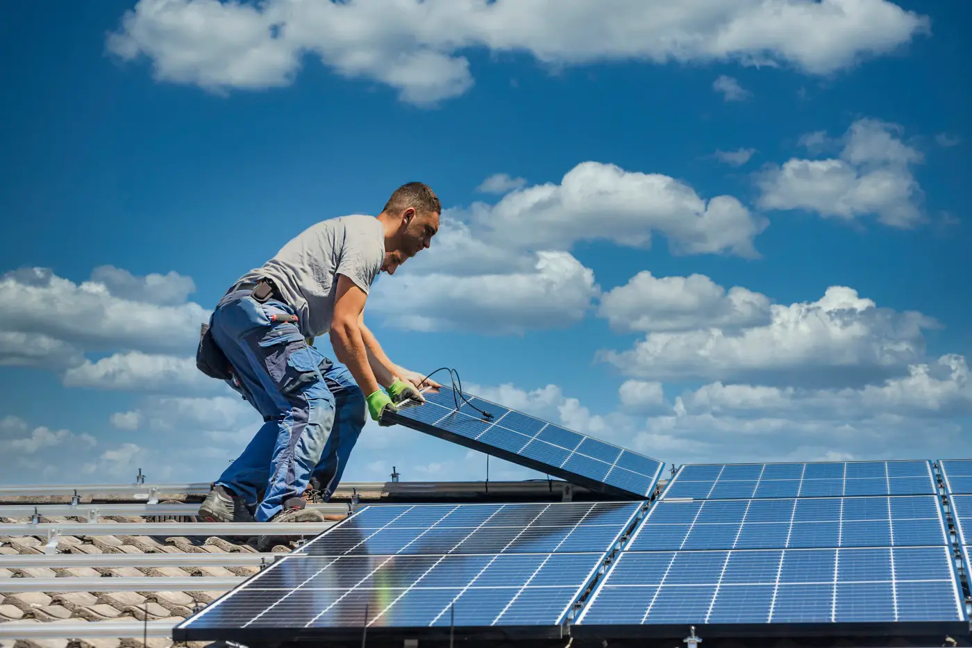 Deux techniciens qui désinstallent des panneaux solaires sur un toit