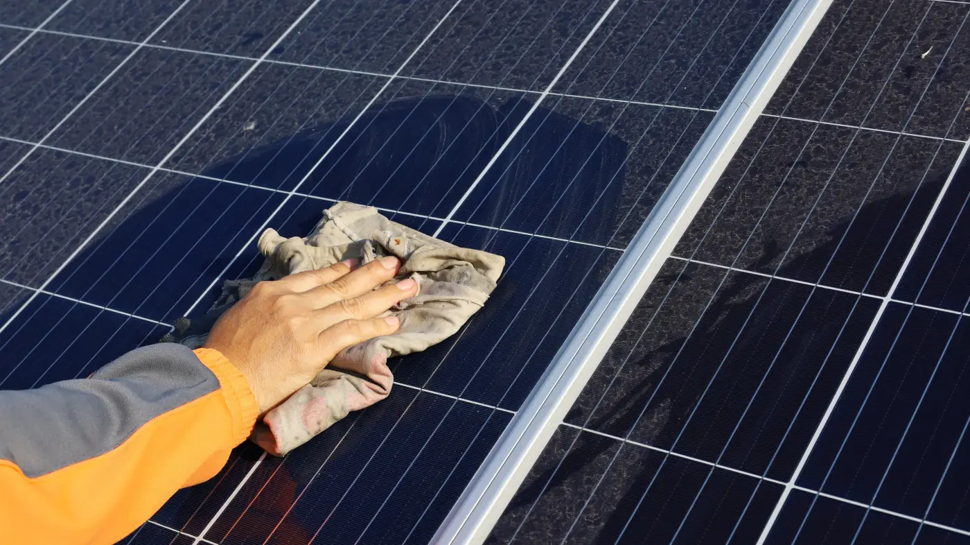 une main nettoyant des panneaux solaires.