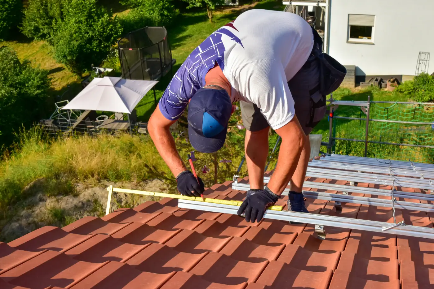 Couvreur installant une installation photovoltaïque sur une toiture : mesure du support pour les pinces du système de rails sur les chevrons du toit