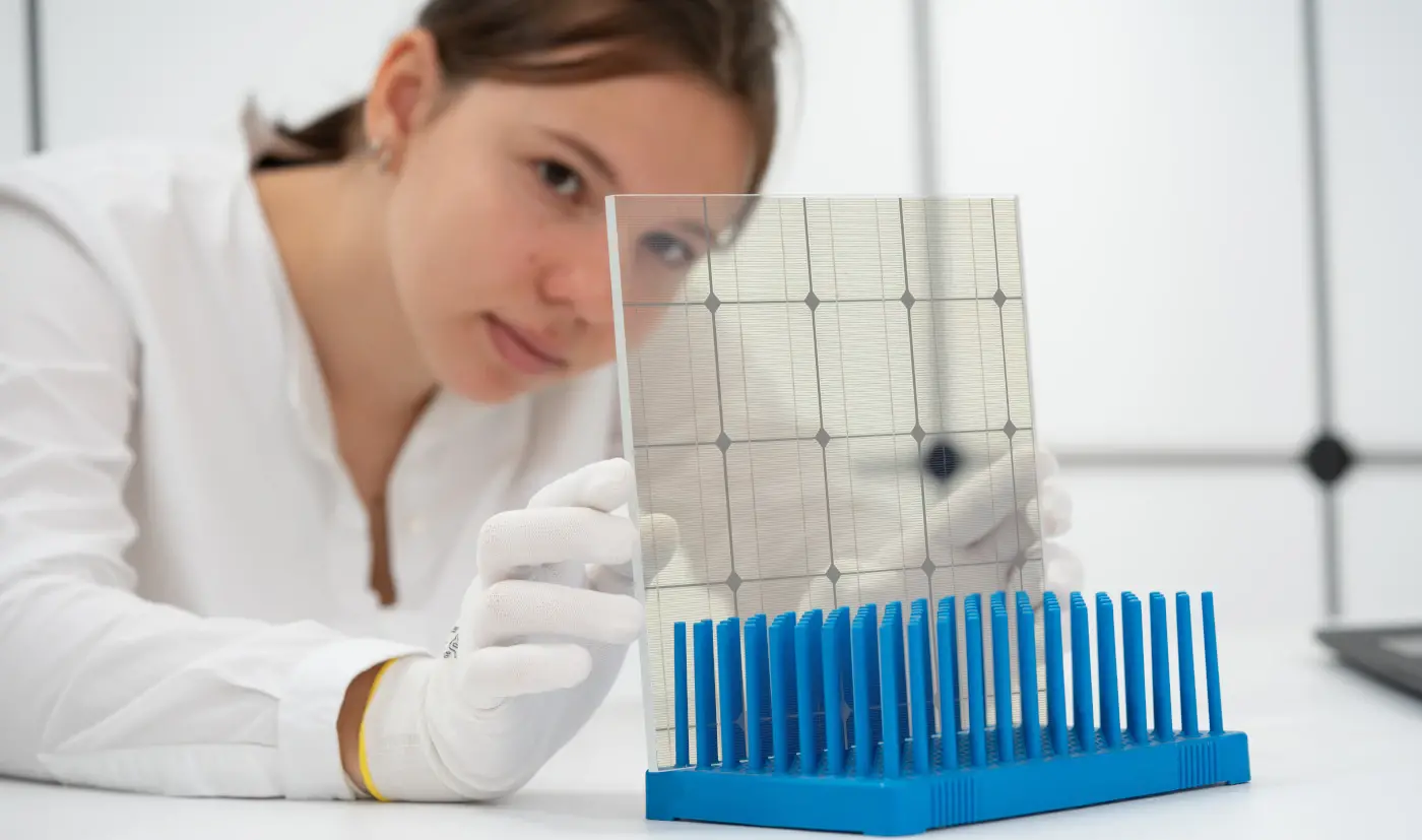 une jeune femme contôle la qualité de panneaux solaires transparents dans un laboratoire d'énergies renouvelables