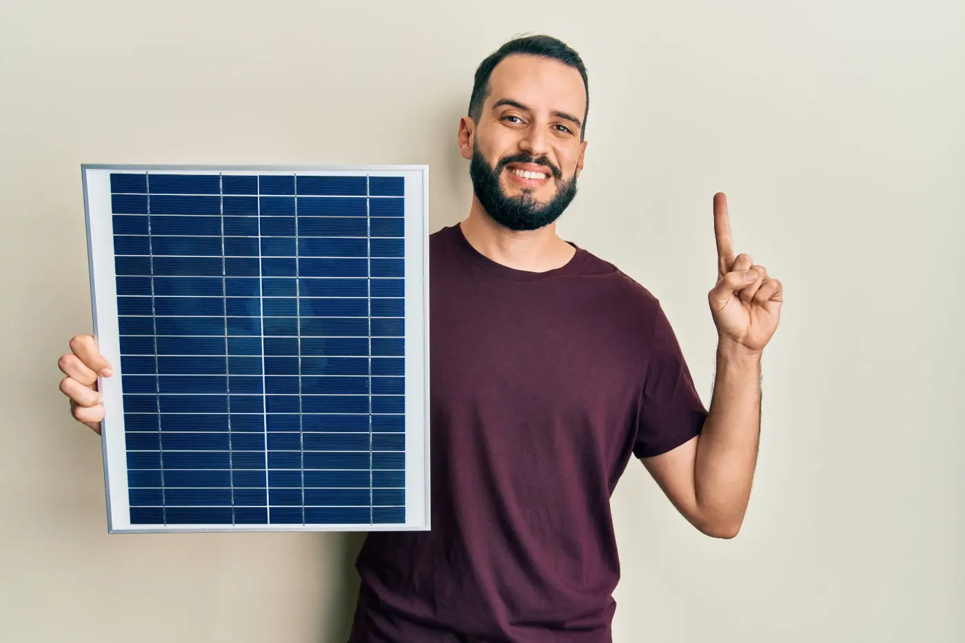 Un homme tient un panneau solaire et lève son index