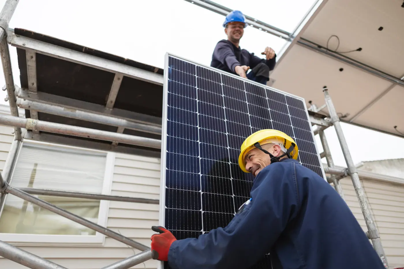 homme soulevant un panneau solaire sur le dessus d'un toit