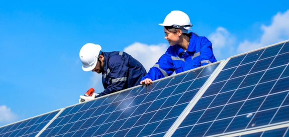 un homme et une femme portant des casques de chantier blanc qui installent des panneaux solaires