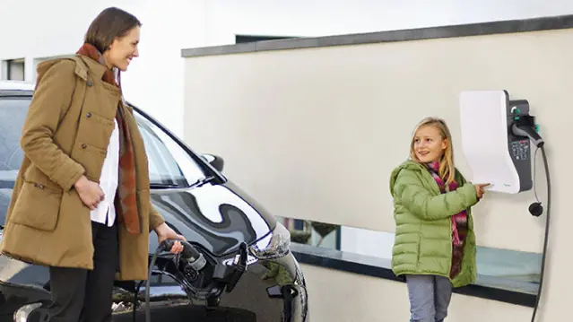 Famille à coté d'une voiture électrique en train de charger